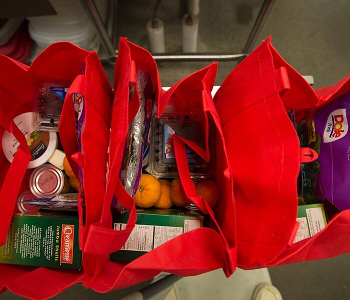 Groceries in red reusable bags.